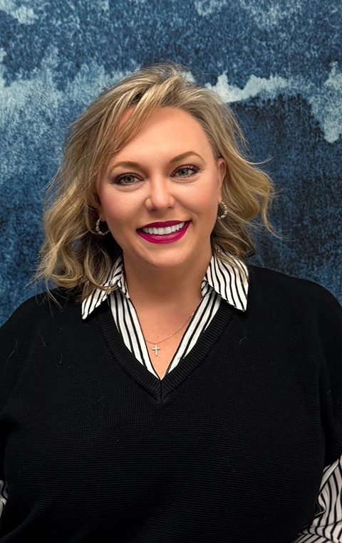 Melissa Shelton smiling in front of a blue wall.