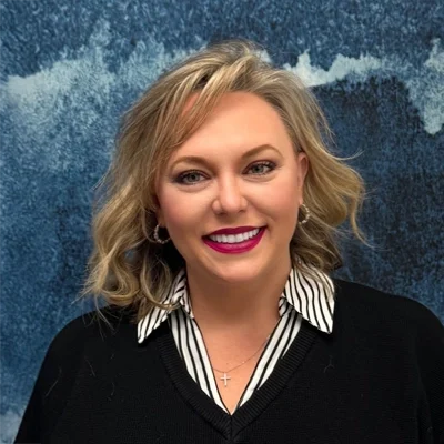 Chiropractor Plano TX Melissa Shelton Meet The Team Melissa Shelton smiling in front of a blue wall.